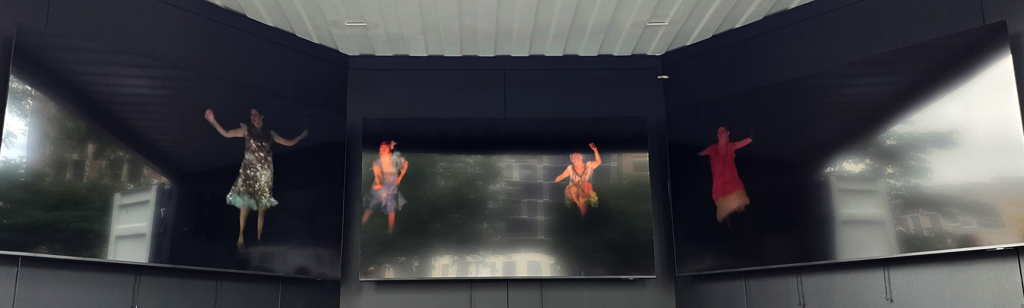 Des danseuses apparaissent sur les trois écrans de Pidikwe.