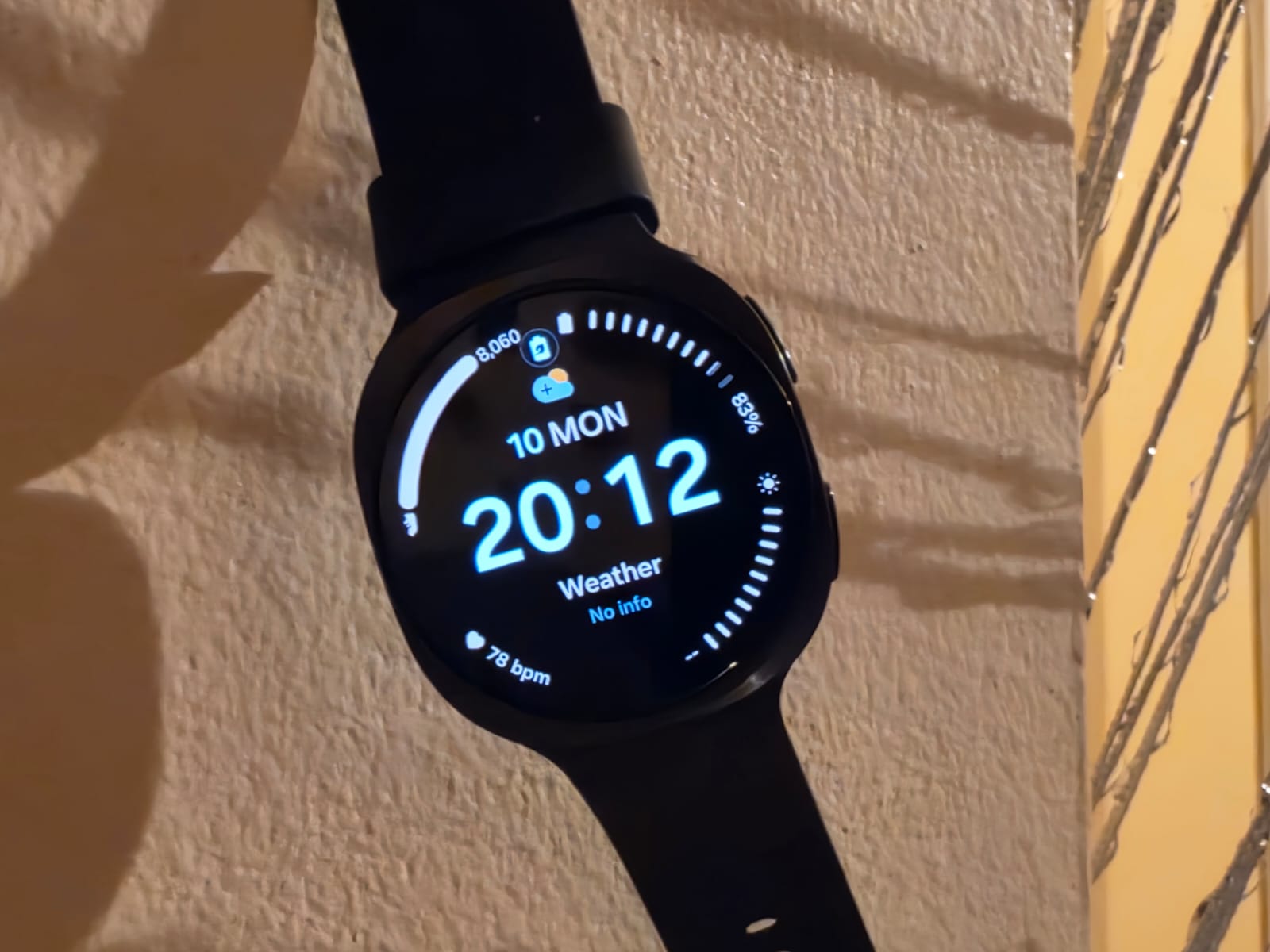 Galaxy Watch9 noire suspendue devant un mur avec des jeux d’ombre