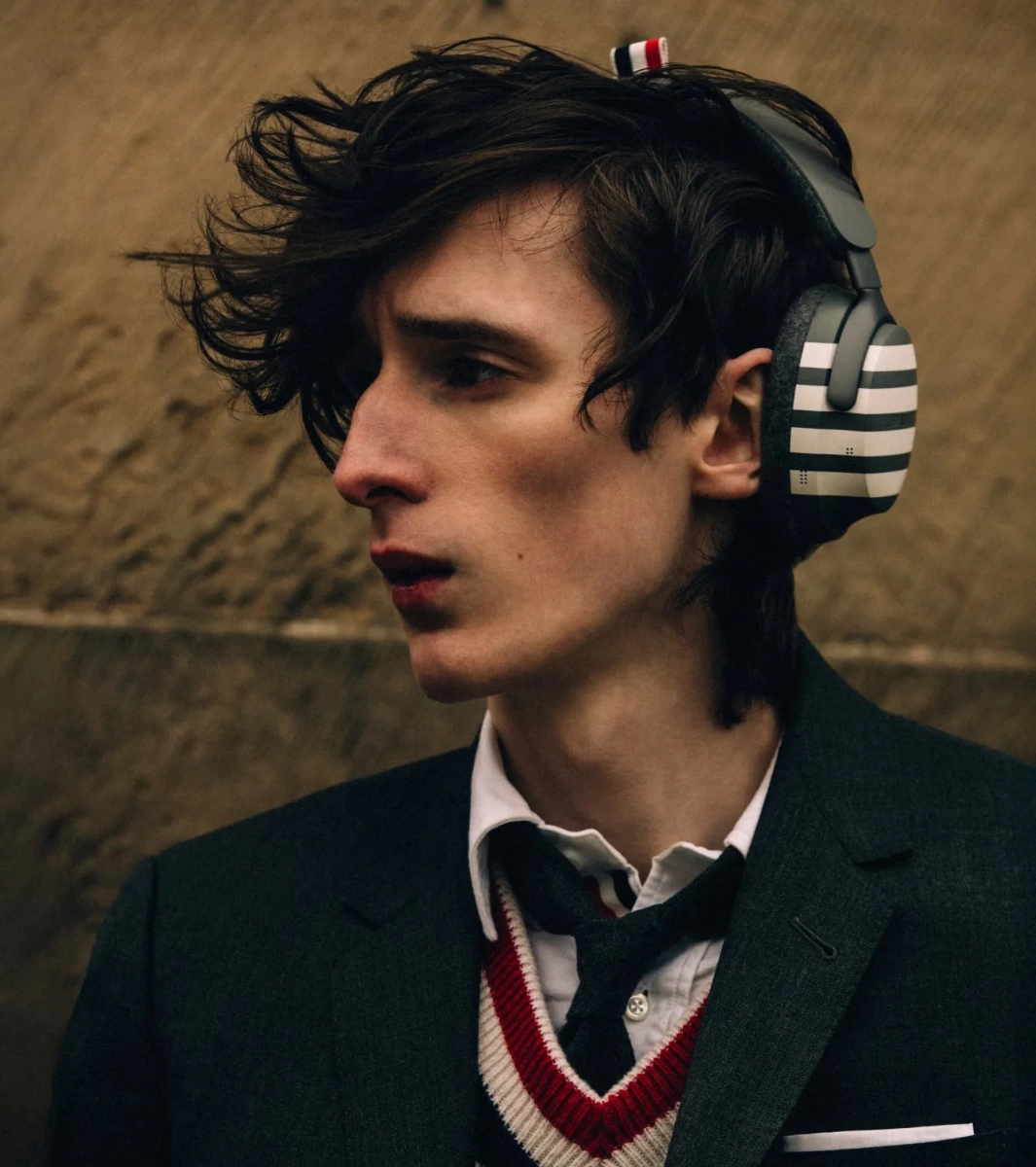 Homme en costume et cravate portant le casque Bose x Thom Browne à rayures grises et blanches
