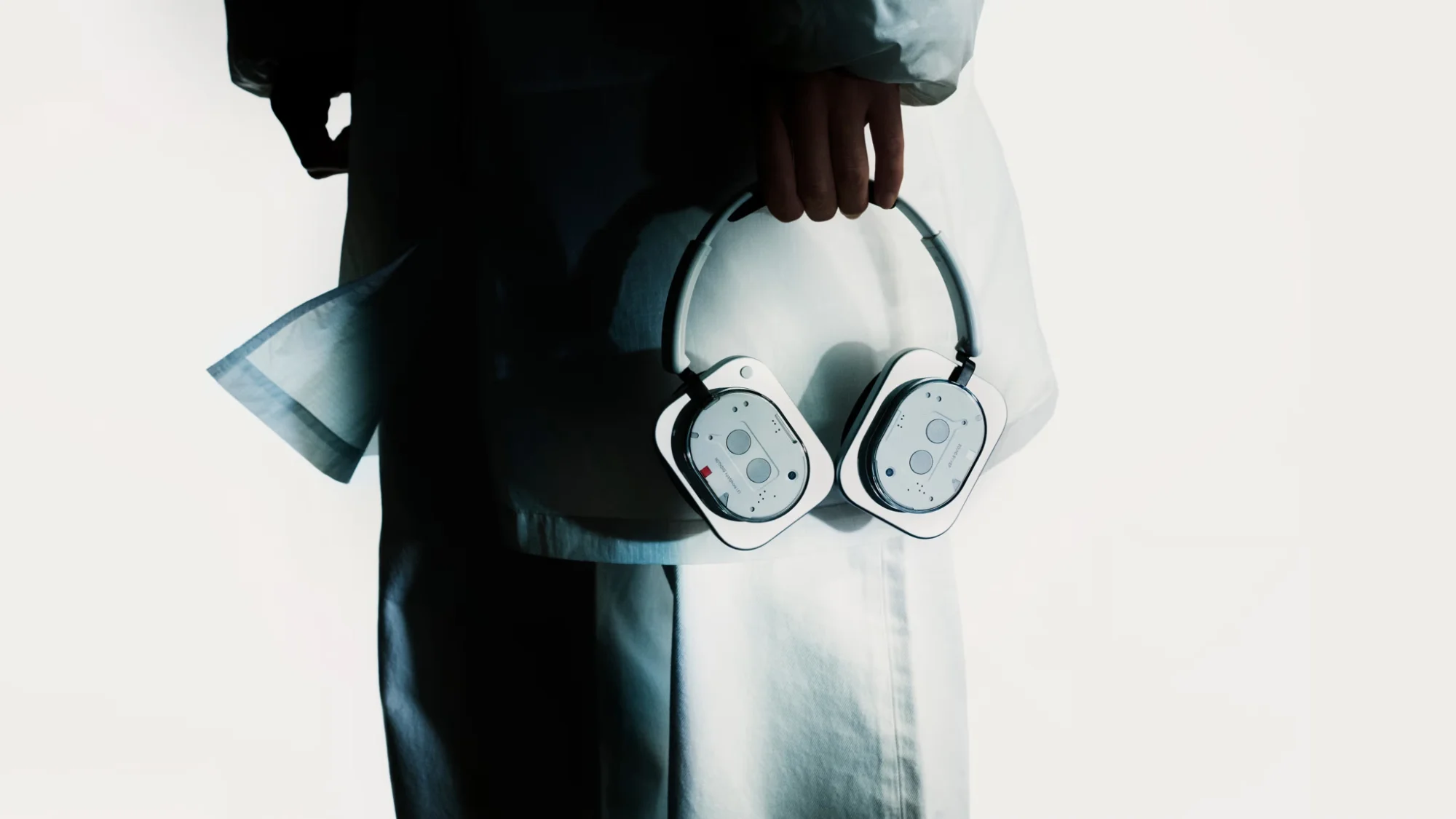 Personne en tenue blanche tenant à la main un casque Nothing Headphone (1) blanc au design transparent